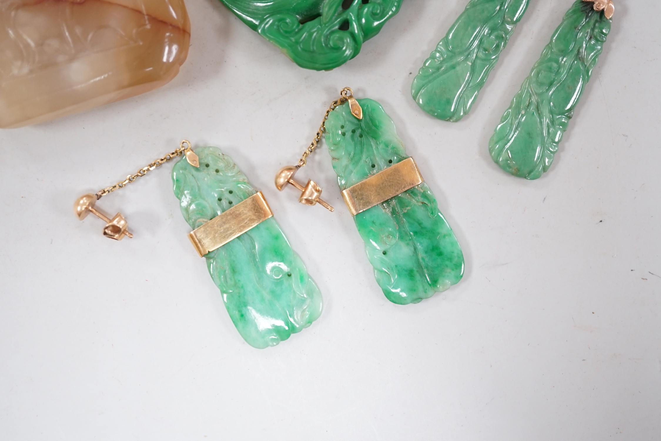 A Chinese carved hardstone pendant, 64mm, a pierced green hardstone pendant on chain and two pairs of yellow metal mounted carved jade earrings.